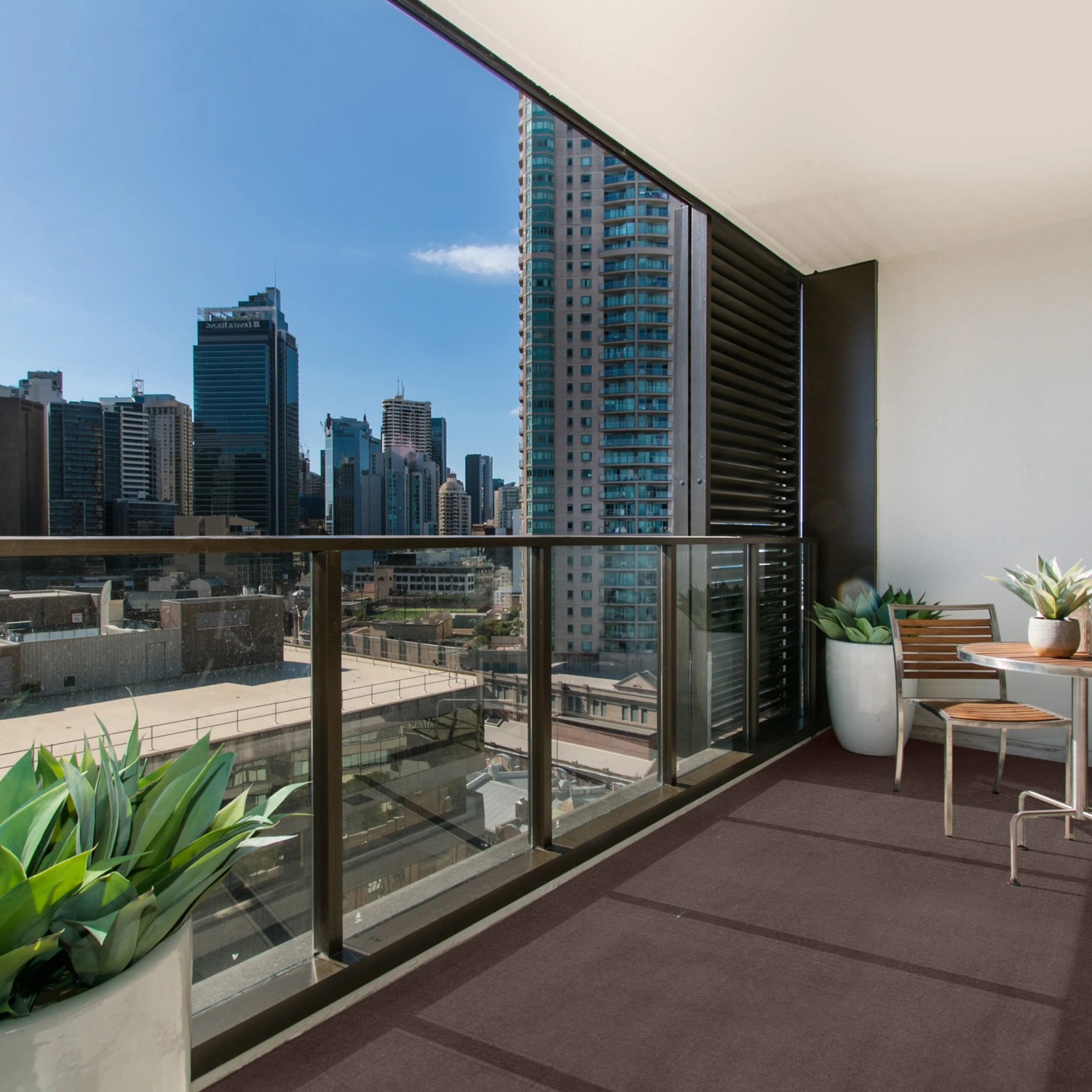 Brauner Primaflor Rasenteppich Comfort auf einem Balkon mit Stadtblick.