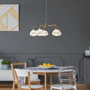 Näve LED-Pendelleuchte Varna, 5-flammig, messingfarben mit irisierenden Gläsern über Esstisch.