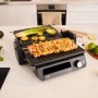 Grauer Braun Multigrill mit Grillgut. Kontaktgrill mit Thermostat für Küche und Haushalt.