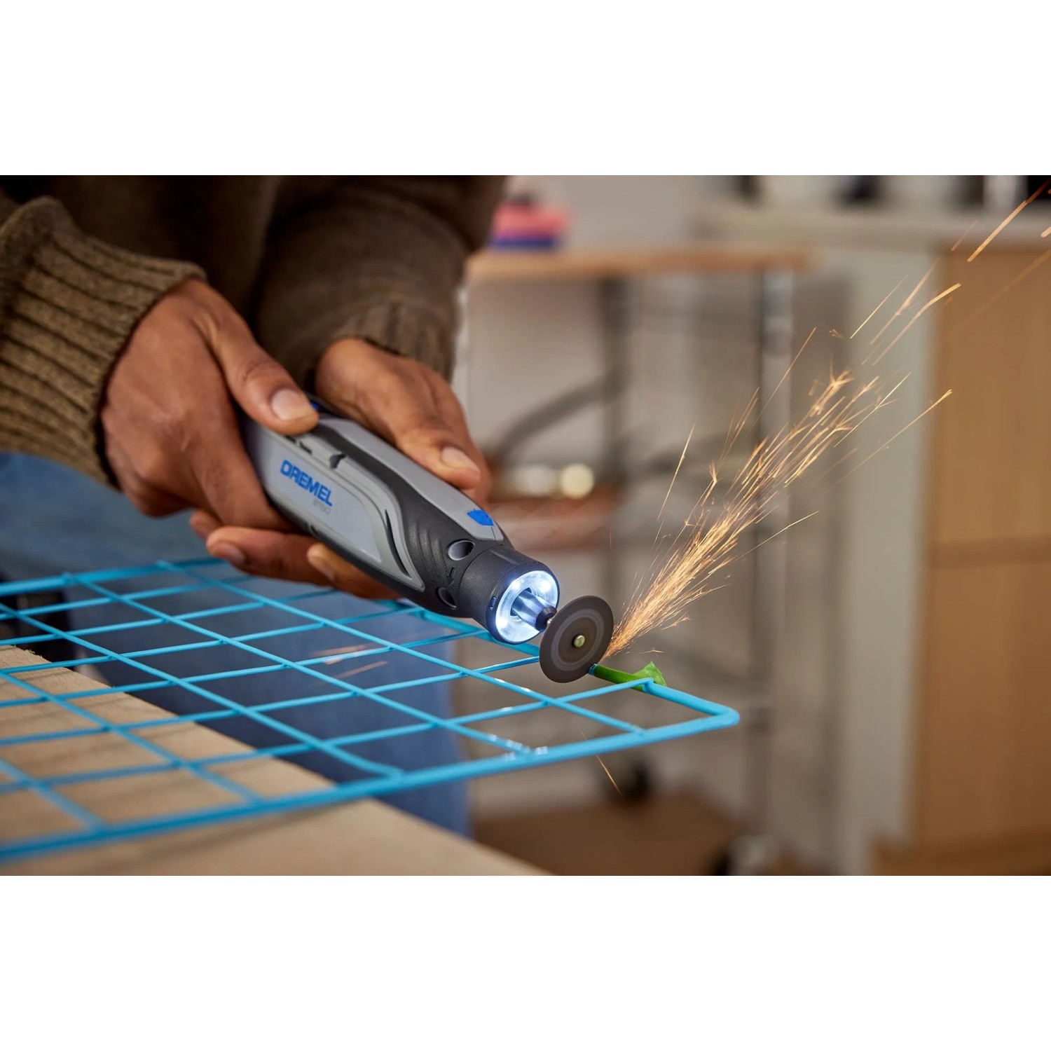 Dremel 8150-20 Akku-Multifunktionswerkzeug im Einsatz beim Schneiden eines Metallgitters, Funken fliegen.