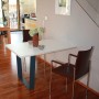 Schwarzes Tischuntergestell in V-Form (700x710mm) unter weißer Tischplatte im Wohnraum.