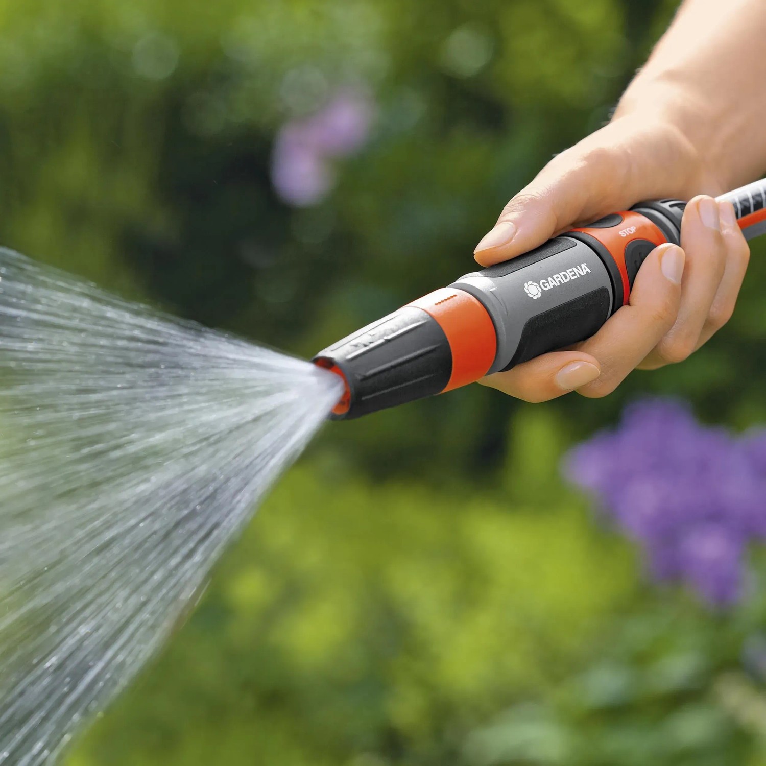 Gardena Reinigungsspritze in Aktion: Hand hält Spritze, Wasserstrahl ist sichtbar.