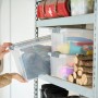Transparente Rotho Stapelbox Compact A4, 13 l, mit Deckel und Klickverschluss im Regal.