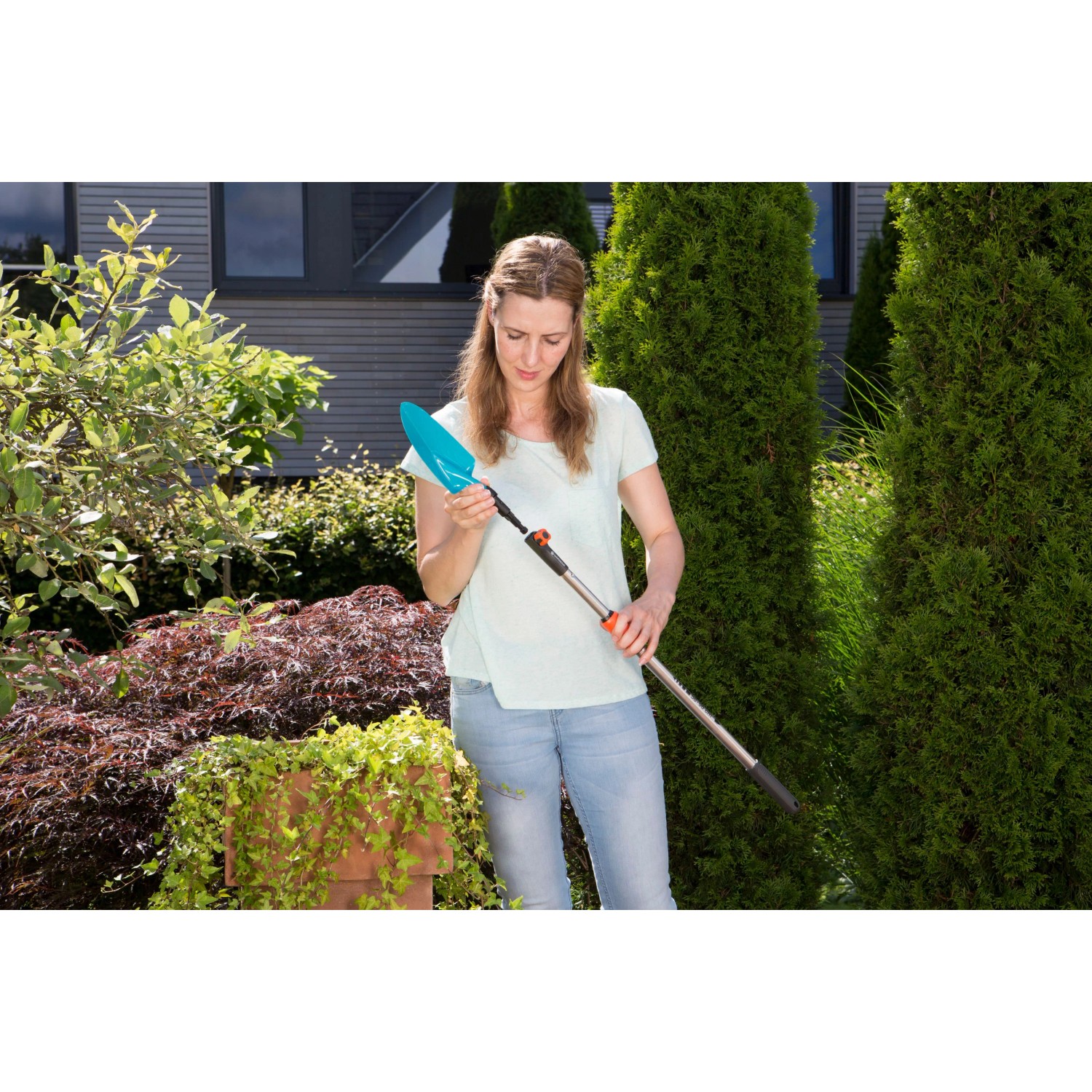 Frau mit Gardena combisystem Blumenkelle mit Stiel im Garten.