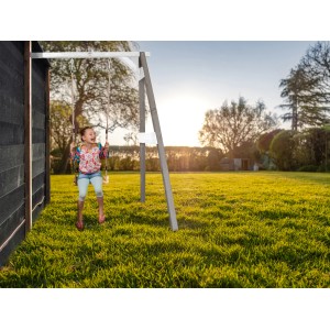 Axi Anbauschaukel in Grau/Weiß mit Kind beim Schaukeln im Garten.