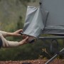 Person verstaut braunen Schuh in grauer Schuhtasche am Feldbett-Zelt. Praktische Aufbewahrung für Camping.