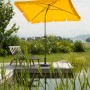 Goldgelber Schneider Balkonschirm Aquila 225x120 cm mit Knickfunktion auf Terrasse am Wasser.