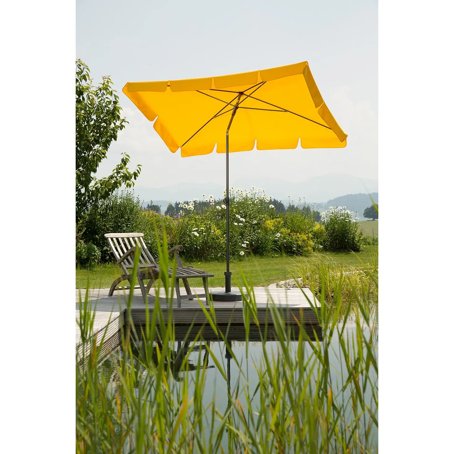 Goldgelber Schneider Balkonschirm Aquila 225x120 cm mit Knickfunktion auf Terrasse am Wasser.