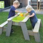 EXIT Aksent Sand-, Wasser- und Picknicktisch mit 2 Kindern beim Spielen im Garten.