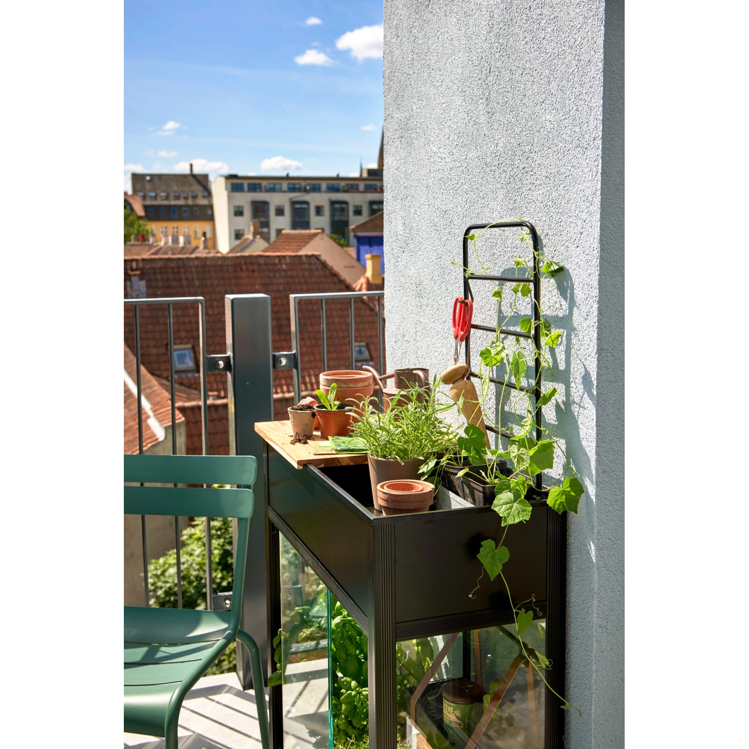 Juliana Gewächshaus Urban Vertical auf Balkon mit Pflanzen, Arbeitsfläche und Rankgitter.