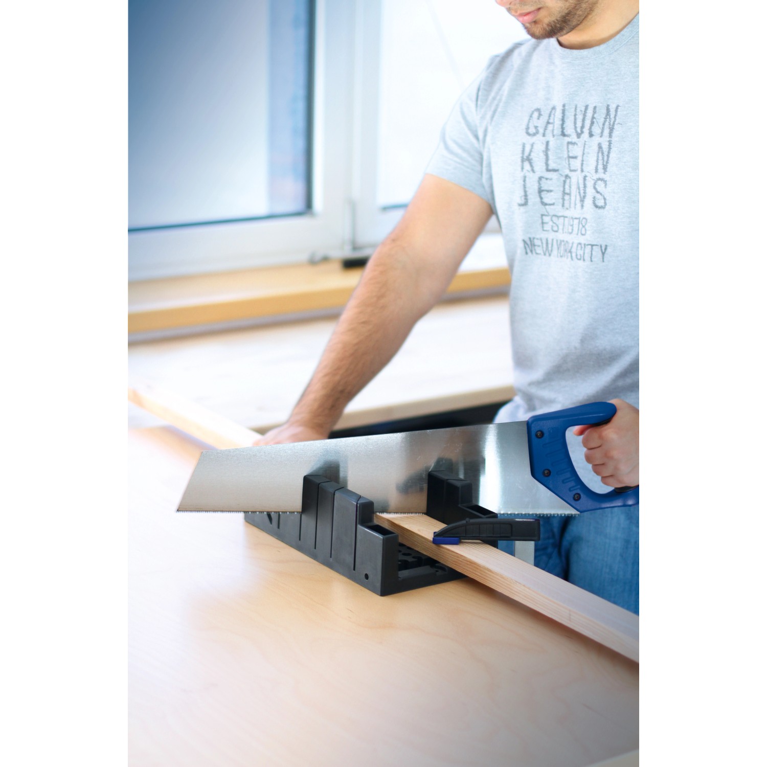 Mann sägt Holz mit LUX Gehrungsschneidlade 300 mm und Handsäge. Winkeleinstellungen fixierbar.