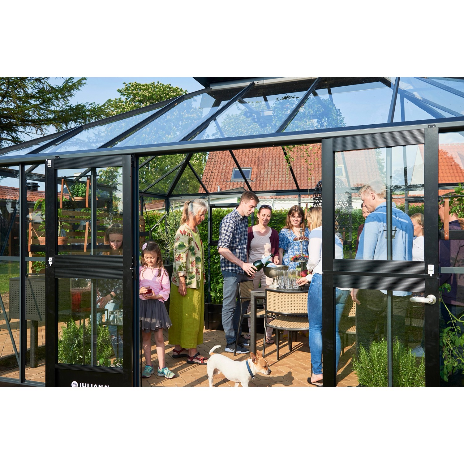 Juliana Gewächshaus Grand Oase 18, anthrazit-schwarz, mit Familie und Hund im Garten.