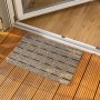 Beige Astra Türmatte Perfo Rips, 40x60 cm, vor einer Tür auf Holzterrasse.