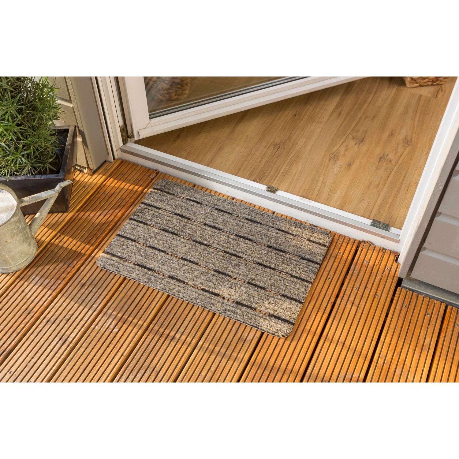 Beige Astra Türmatte Perfo Rips, 40x60 cm, vor einer Tür auf Holzterrasse.