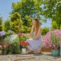 Frau bewässert Blumen mit Gardena Bewässerungsbrause AquaCount im Garten.