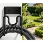 Schwarzer wandmontierter Schlauchhalter aus Eisen mit aufgerolltem Gartenschlauch im Garten.