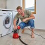 Mann bedient rote Einhell GC-DP 6935 LL Schmutzwasserpumpe im Keller neben Waschmaschinen.