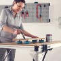 Frau lackiert Holz auf Werkbank mit wolfcraft Werkstückauflagen-Set.