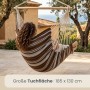 Gestreifter AMANKA Hängesessel aus Baumwolle mit Holzstab, in dem eine Person auf einer Terrasse entspannt. Ideal für Garten & Balkon.