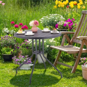 Runder grauer Gartentisch in Holzoptik aus Kunststoff und Stahl, gedeckt im Garten.