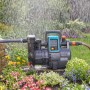 Gardena Haus- und Gartenautomat 4000/5 im Einsatz: Graue Gartenpumpe mit blauem Display bewässert Blumen.