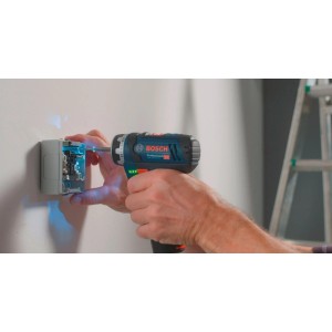 Kompakter blauer Bosch Professional Akku-Bohrschrauber GSR 12V-15 FC beim Schrauben in eine Wandsteckdose.