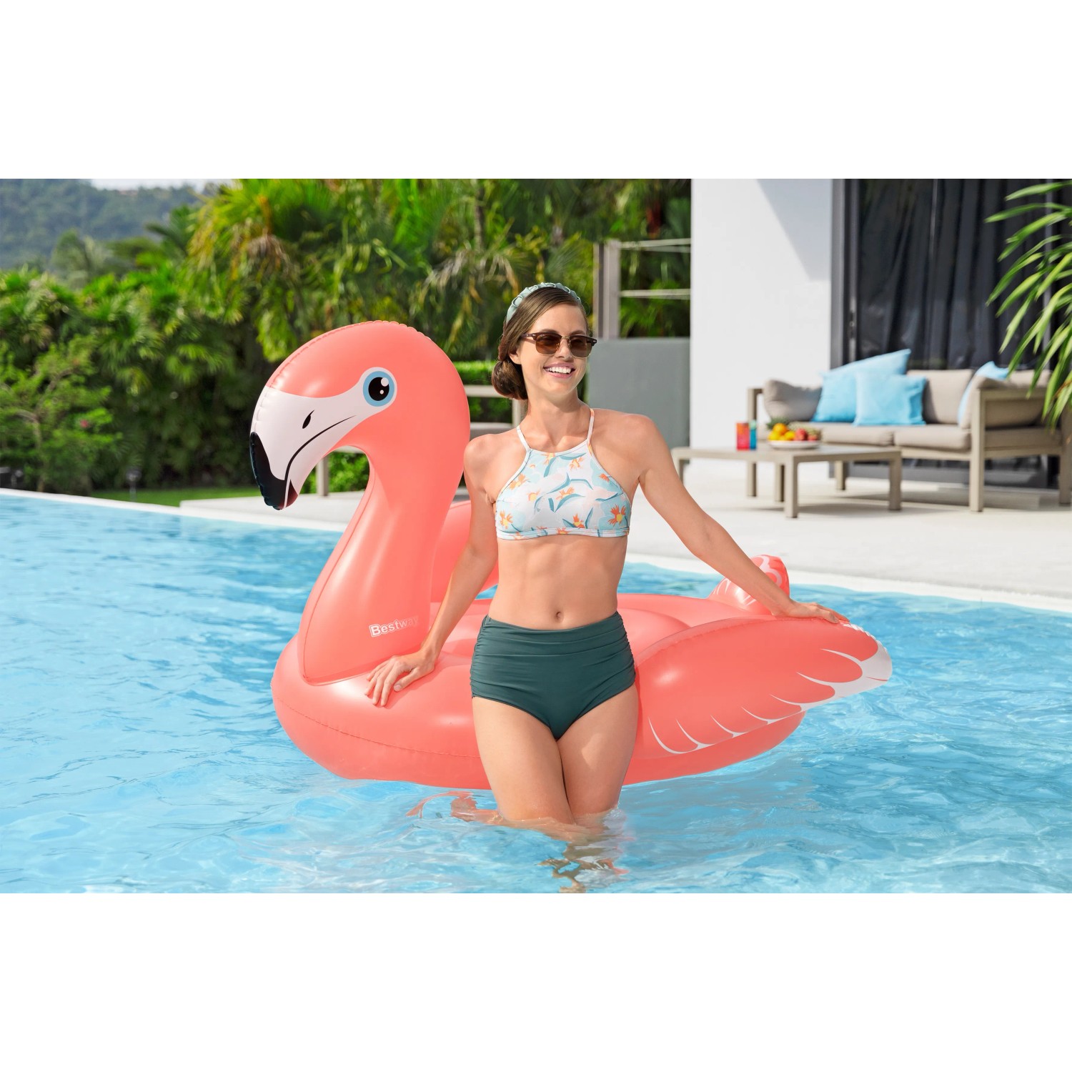Frau mit Bestway® Schwimmtier Flamenco™ im Pool. Aufblasbarer Flamingo in Rosa.