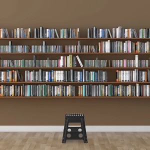 Schwarzer Relaxdays Klapphocker aus Kunststoff, faltbar, rutschfest, vor Bücherregal. Vielseitiger Haushaltshocker.
