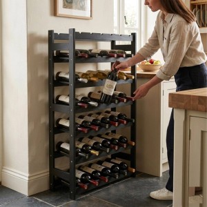Schwarzes Weinregal aus Walnussholz für 42 Flaschen, gefüllt mit Rot- und Weißwein. Eine Person entnimmt eine Flasche.
