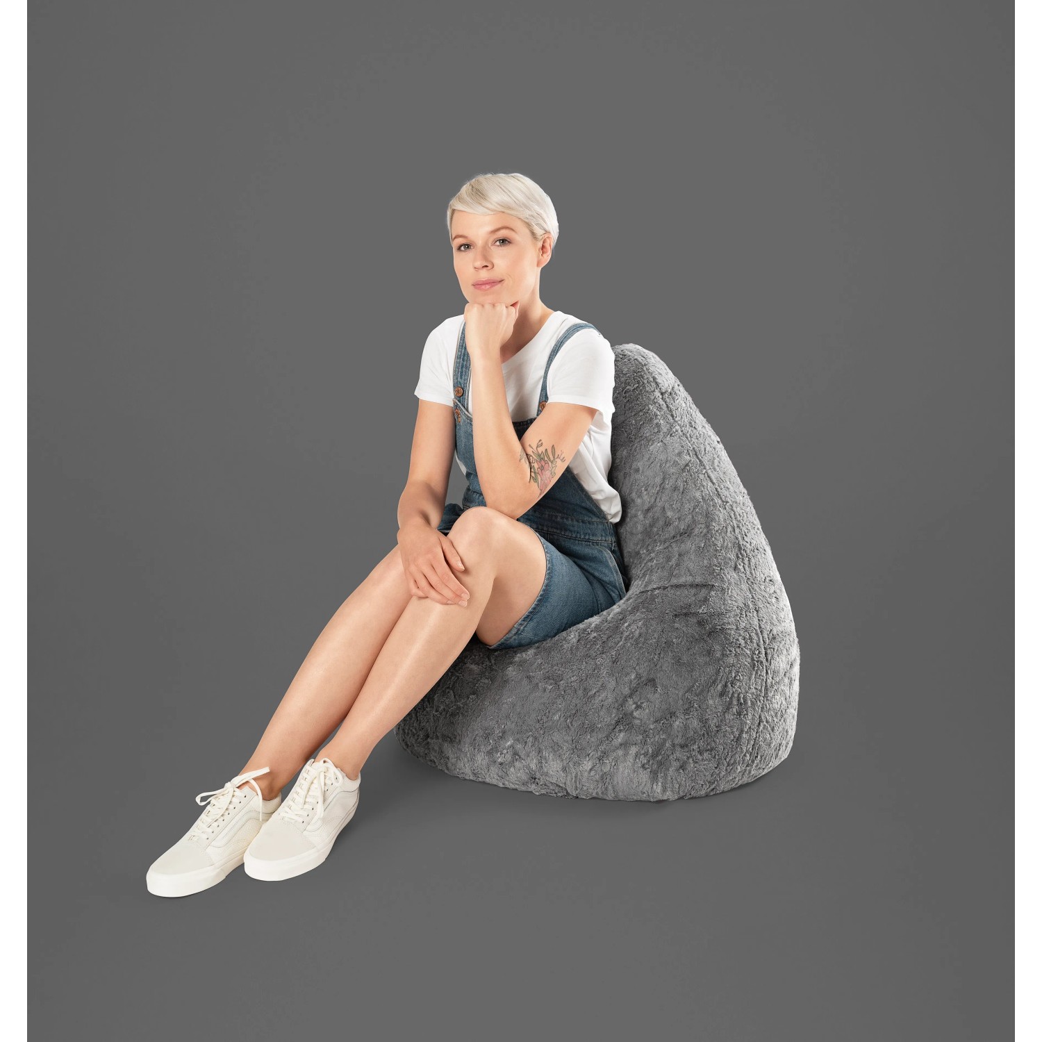 Frau sitzt im grauen Sitting Point Sitzsack Fluffy 220l. Bequemer Plüsch-Sitzsack für entspannte Stunden.