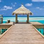 Komar Fototapete Vlies Beach Resort (100x280 cm) mit Steg und Strandhaus Motiv.