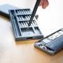 LUX Smartphone-Reparatur-Set, 26-teilig, mit Werkzeug und geöffnetem Smartphone.