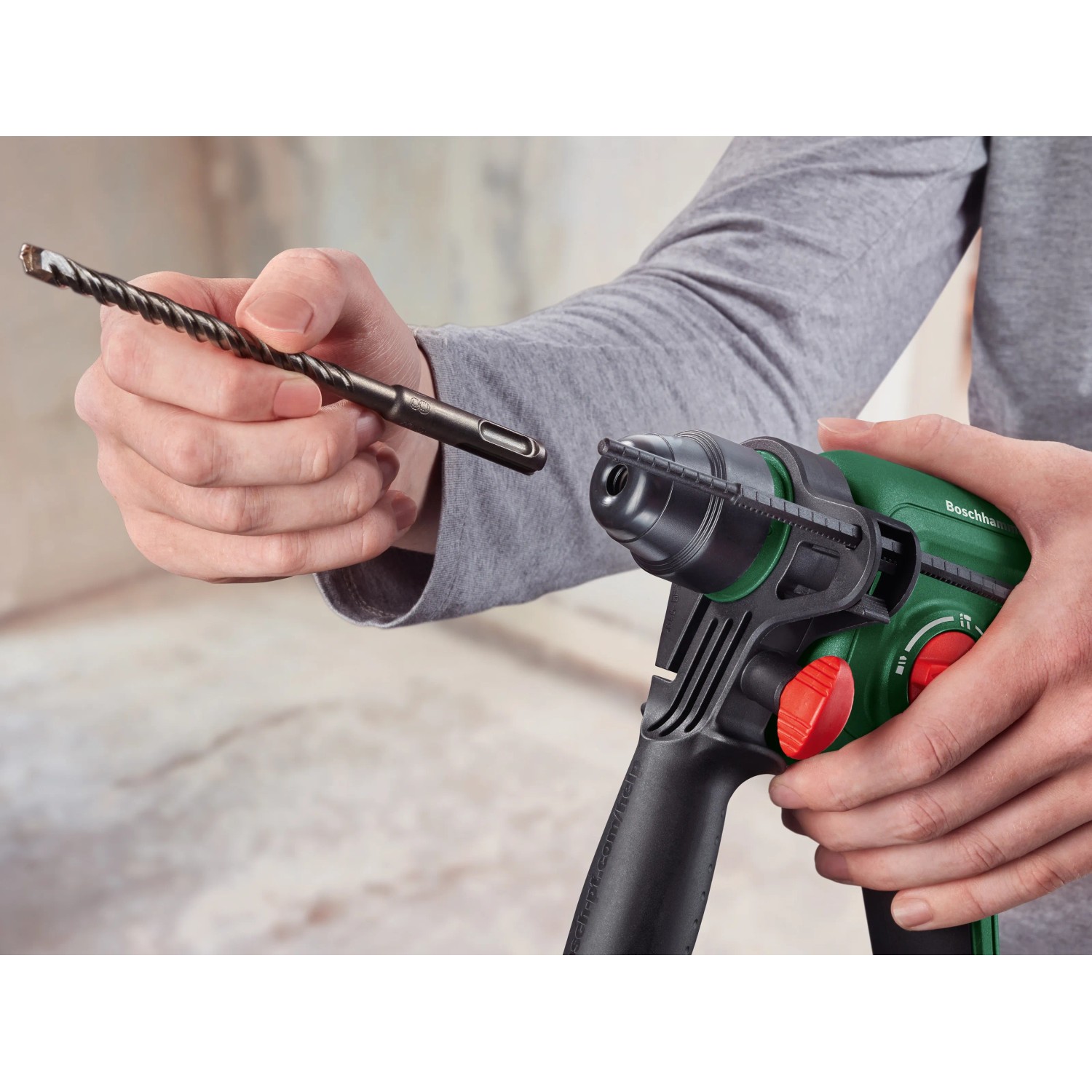 Bosch Akku-Bohrhammer UniversalHammer 18V mit Bohrer in der Hand, SDS-Plus Aufnahme.