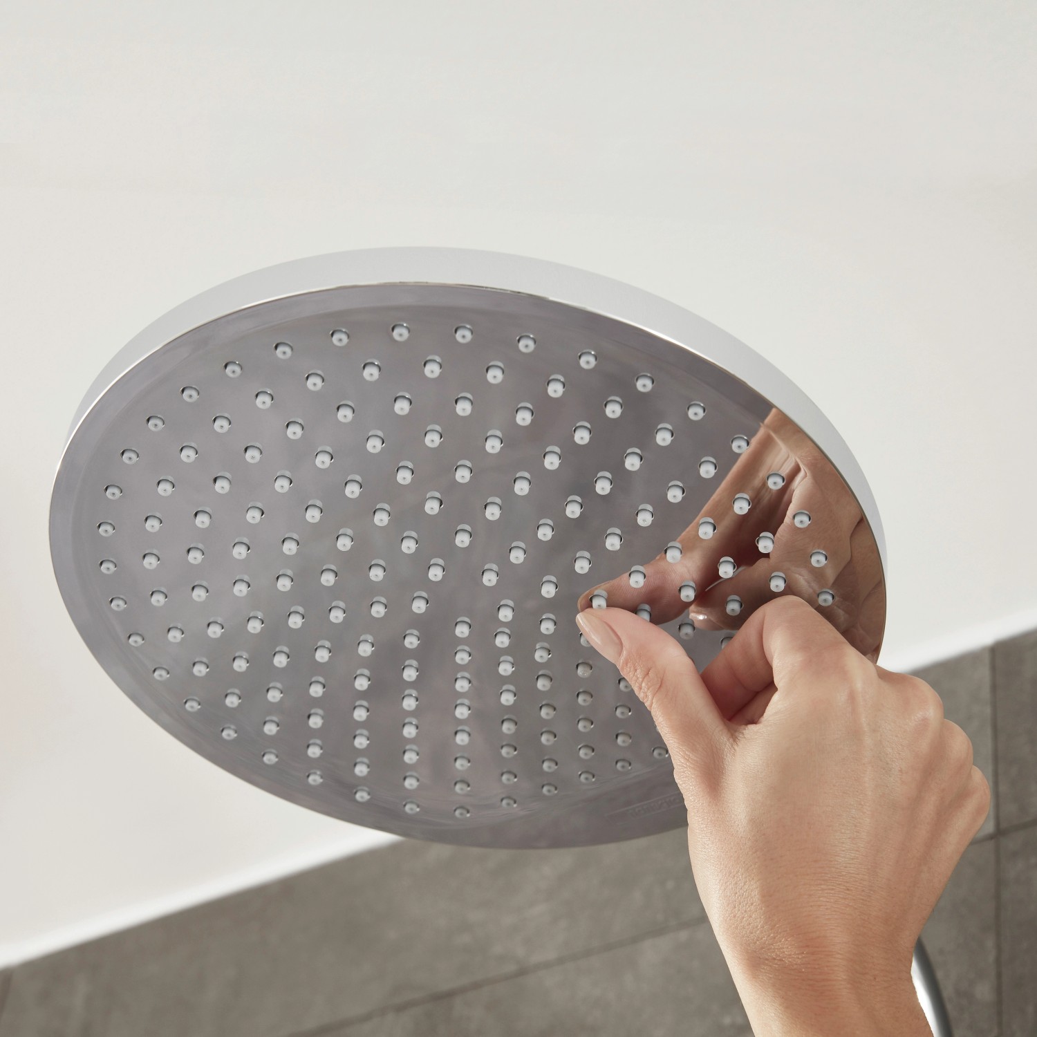 Nahaufnahme einer Hand, die Noppen der Hansgrohe Crometta S 240 Kopfbrause reinigt.