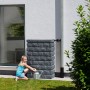 Garantia Wandtank Rocky Junior 300 l Dark Granite mit Mädchen und Gießkanne vor Hauswand.