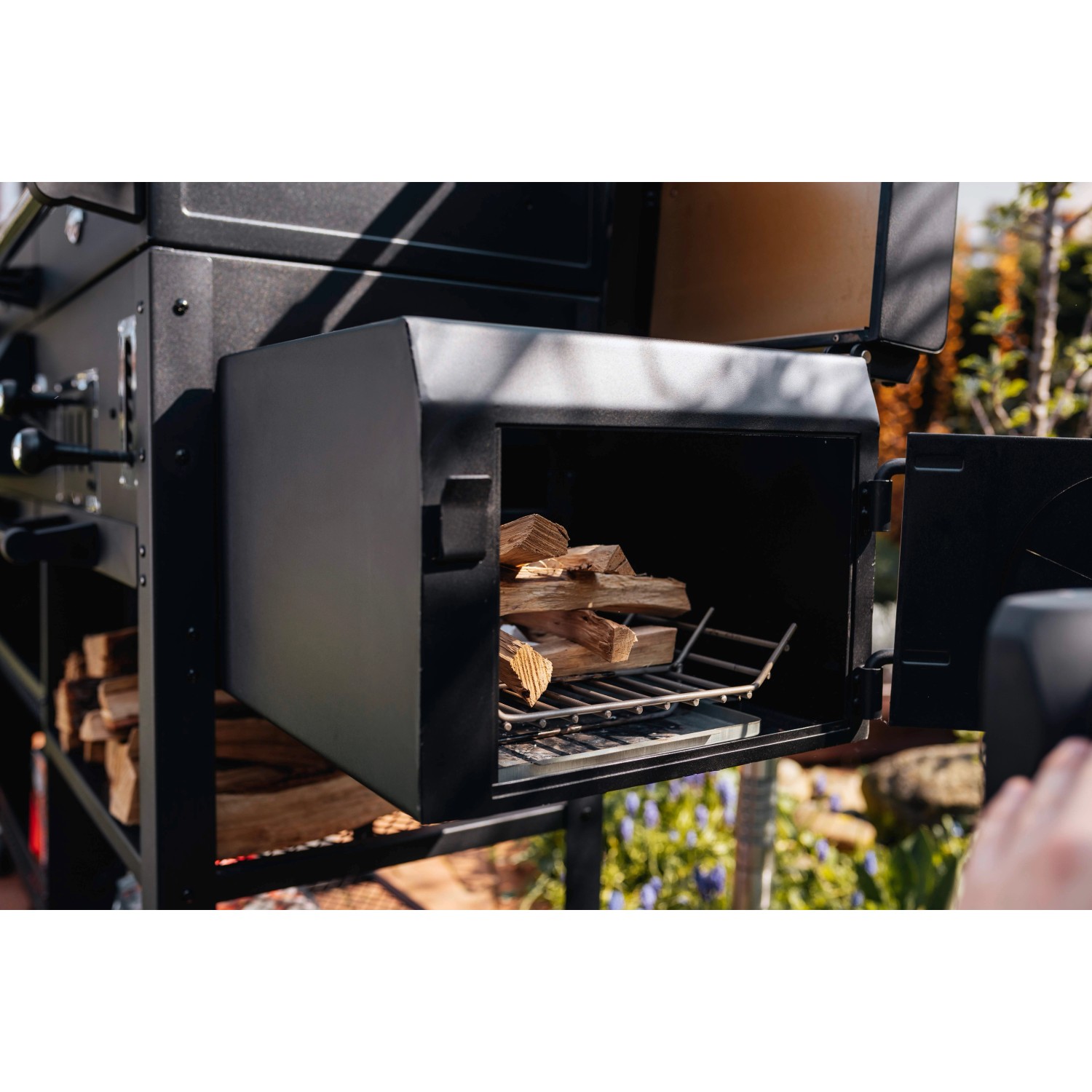 Detailaufnahme des Jamestown Kombigrill Drake Smokers mit Holzscheiten im Garraum.