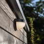 Lutec Solar-Außenwandleuchte Bubble aus Edelstahl an einer Holzwand.