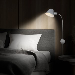 Chrom-matte, schwenkbare Briloner Bettleuchte neben einem Bett.