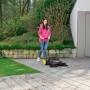 Frau kehrt mit Kärcher Kehrmaschine S 4 Twin Go!Further Gehweg. Inkl. Greifzange.