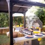Schwarzer Palram Canopia Austin BBQ Pavillon mit Grill und Zubehör im Garten.