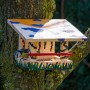 Bemaltes Dobar Vogelfutterhaus aus Kiefernholz mit Blaumeise an Baum.
