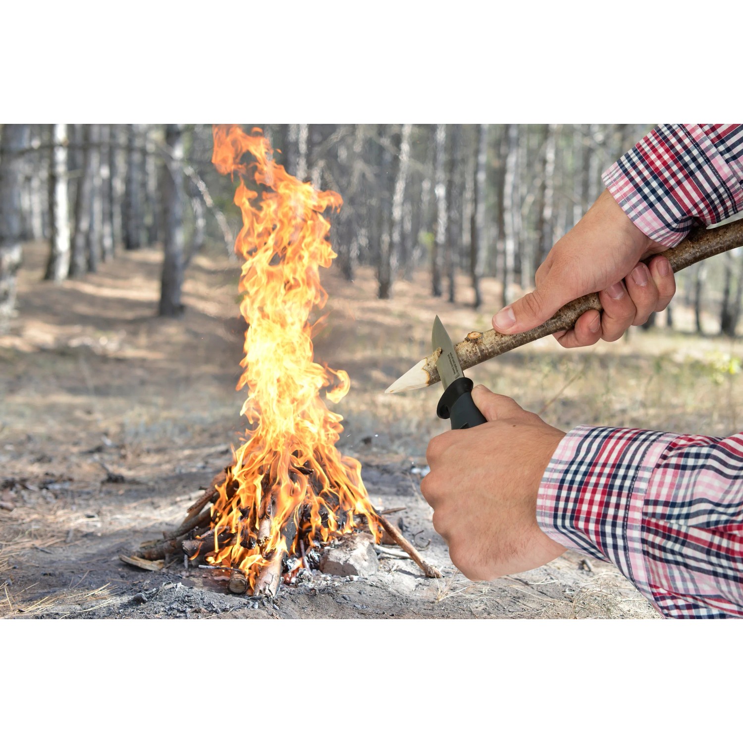 Wolfcraft Outdoormesser in Nutzung beim Anspitzen eines Holzstücks am Lagerfeuer.