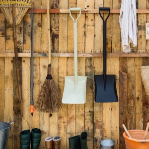 Relaxdays Fugenbürsten Set mit Teleskopstiel und 2 Aufsätzen an einer Holzwand.