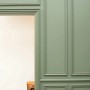 Detailaufnahme: Grüne Wand mit ORAC DECOR Zierleisten DX170, Türumrandung, klassisch, mit Hocker.