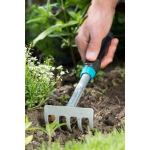 Gardena Comfort Kleingeräte Set: Hand beim Arbeiten mit dem Blumenrechen im Garten.