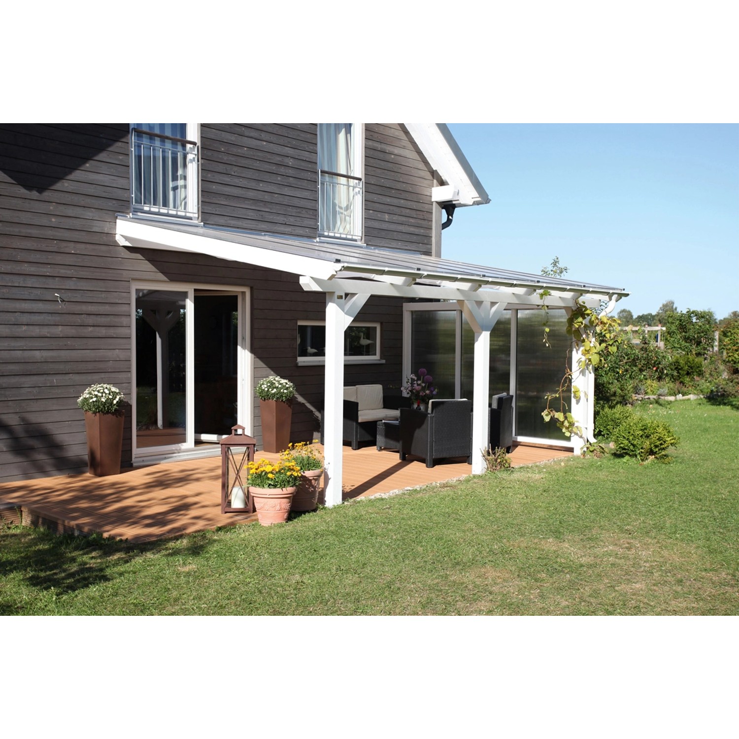 Weiße Skan Holz Terrassenüberdachung Andria mit Polycarbonat-Doppelstegplatten und Gartenmöbeln.