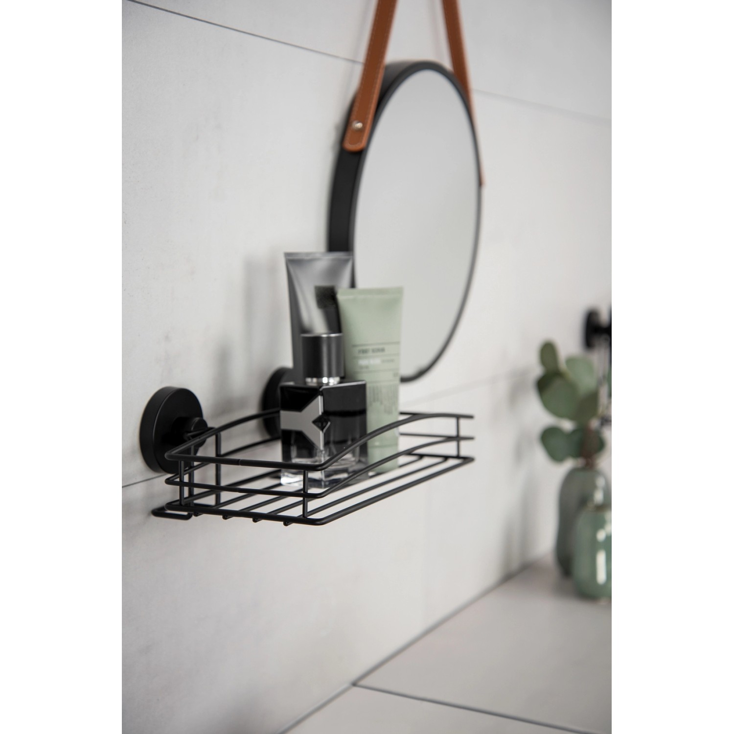 Schwarze Wenko Wandablage Vacuum-Loc mit Badartikeln an weißer Wand.