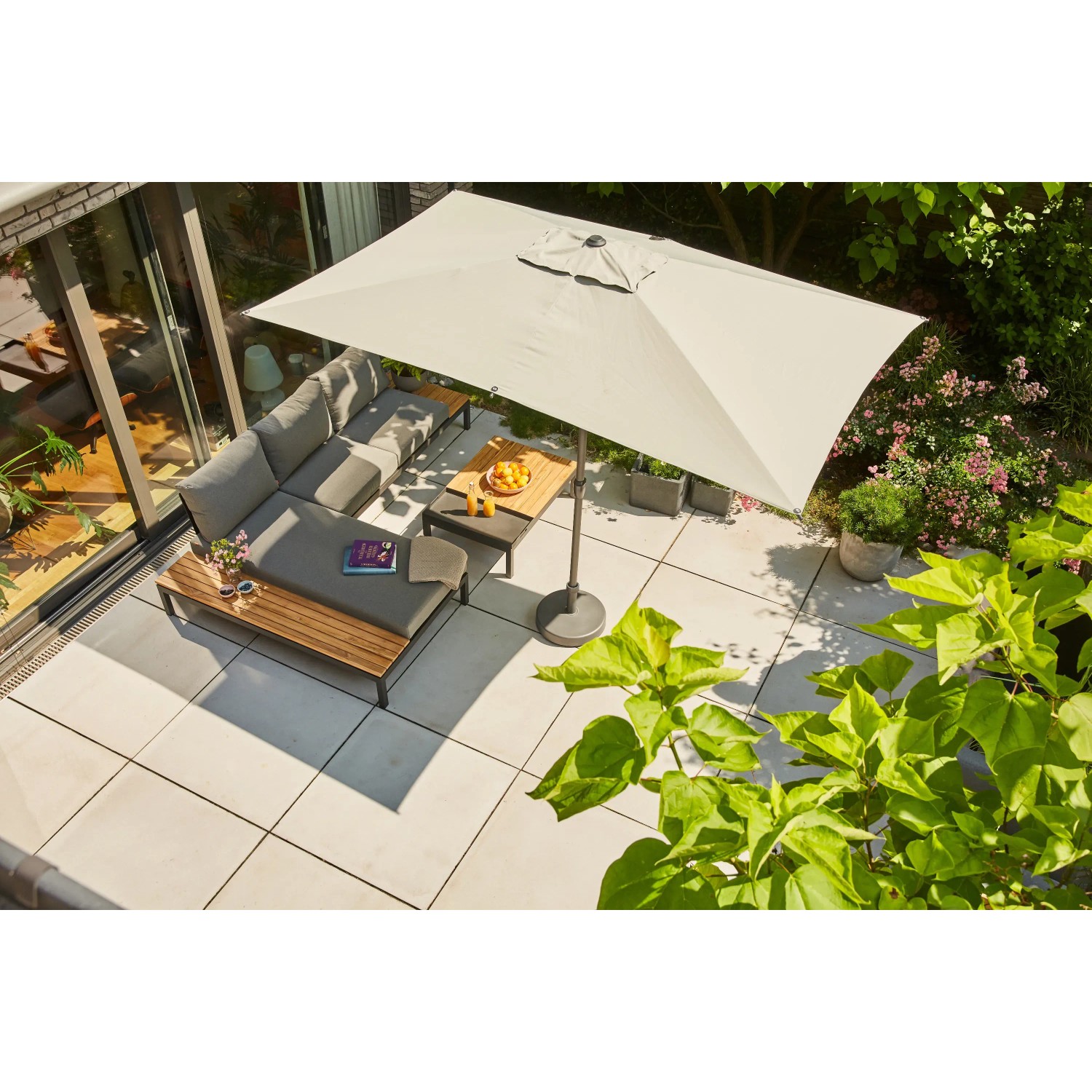 Grauer Siena Garden Marktschirm (200x300 cm) mit Knickfunktion über einer Loungegruppe auf einer Terrasse.