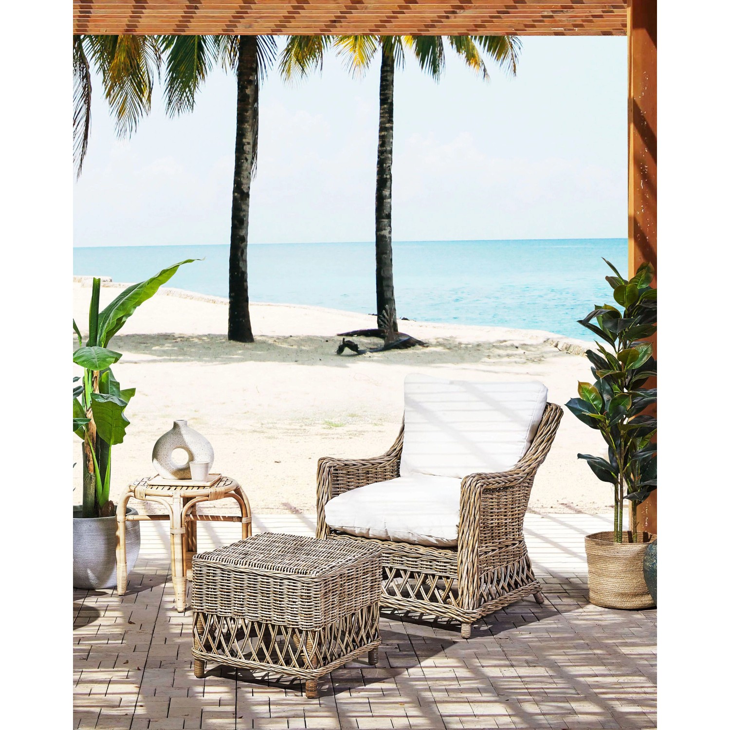 Naturfarbener Beliani Sessel mit Fußhocker und weißen Kissen auf einer Terrasse.