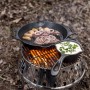Petromax Atago Grill-Set mit Grillspießen beim Outdoor-Kochen mit Pfanne und Topf über dem Feuer.